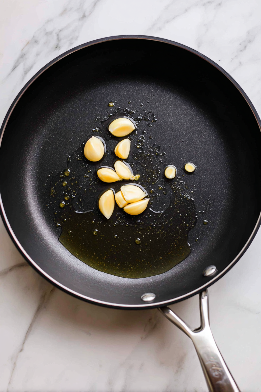 Add whole garlic cloves and sauté until lightly golden.
