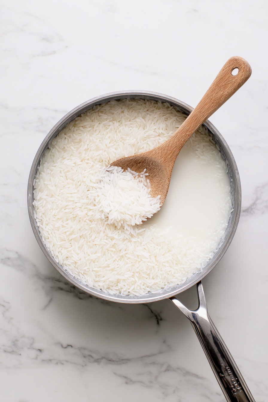 In a saucepan, combine rice, coconut milk, water, and sugar. Bring to a boil, then simmer for 15 minutes until rice is fluffy.