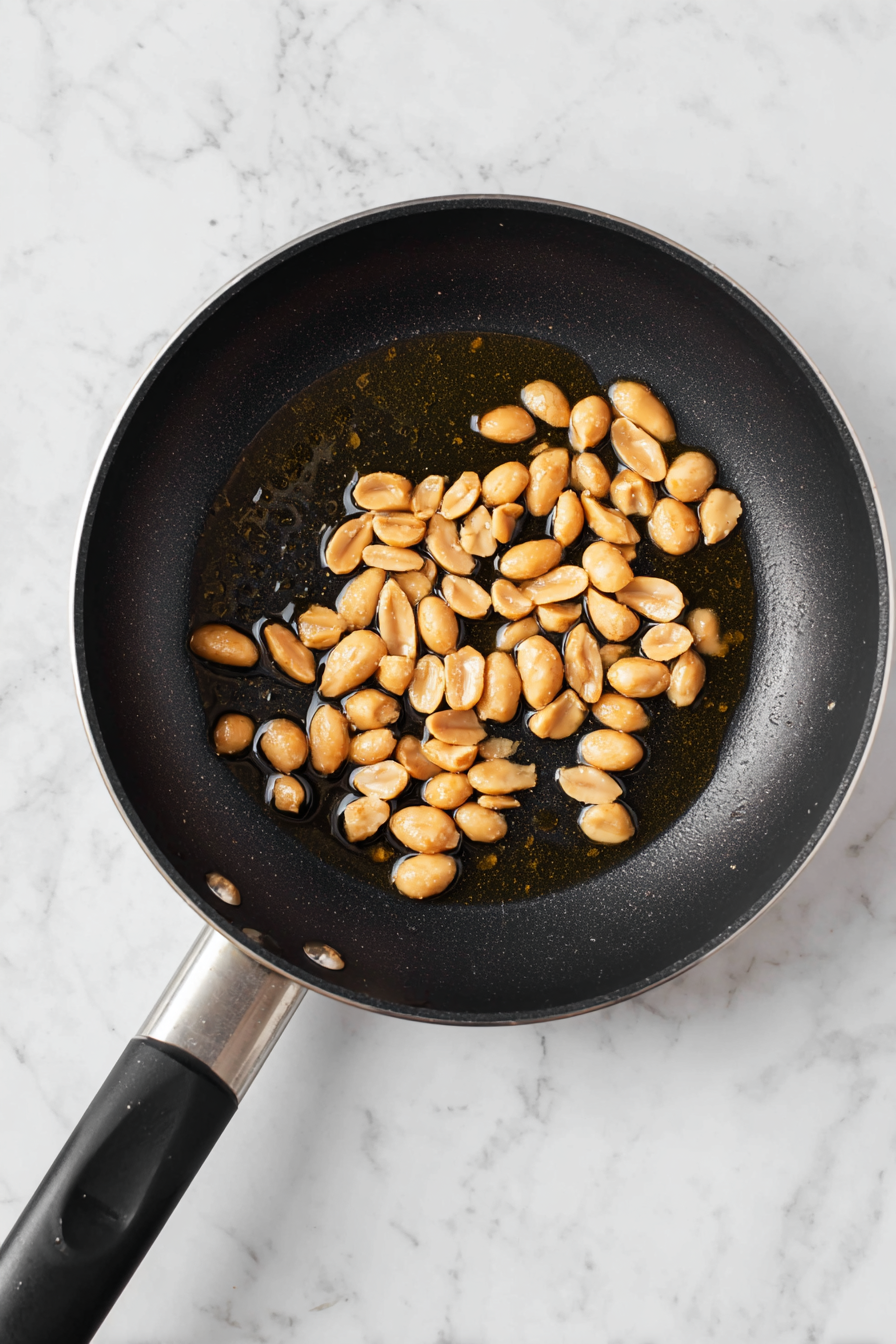 Heat 1 tablespoon oil in a pan, fry peanuts until golden, then remove and set aside.