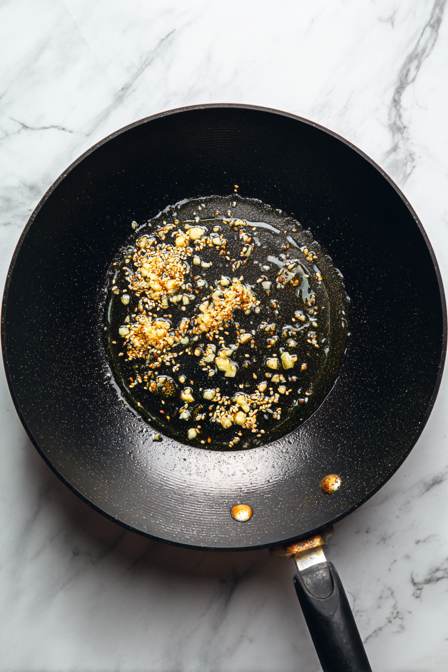 Heat oil and ghee in a kadai, add cumin seeds, then sauté garlic and ginger until golden.