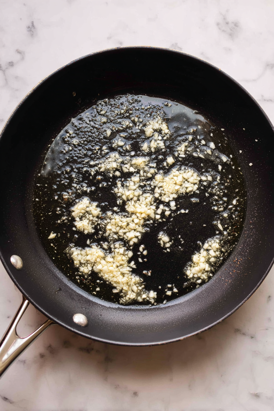 In the same pan, melt butter and sauté minced garlic for 1 minute.