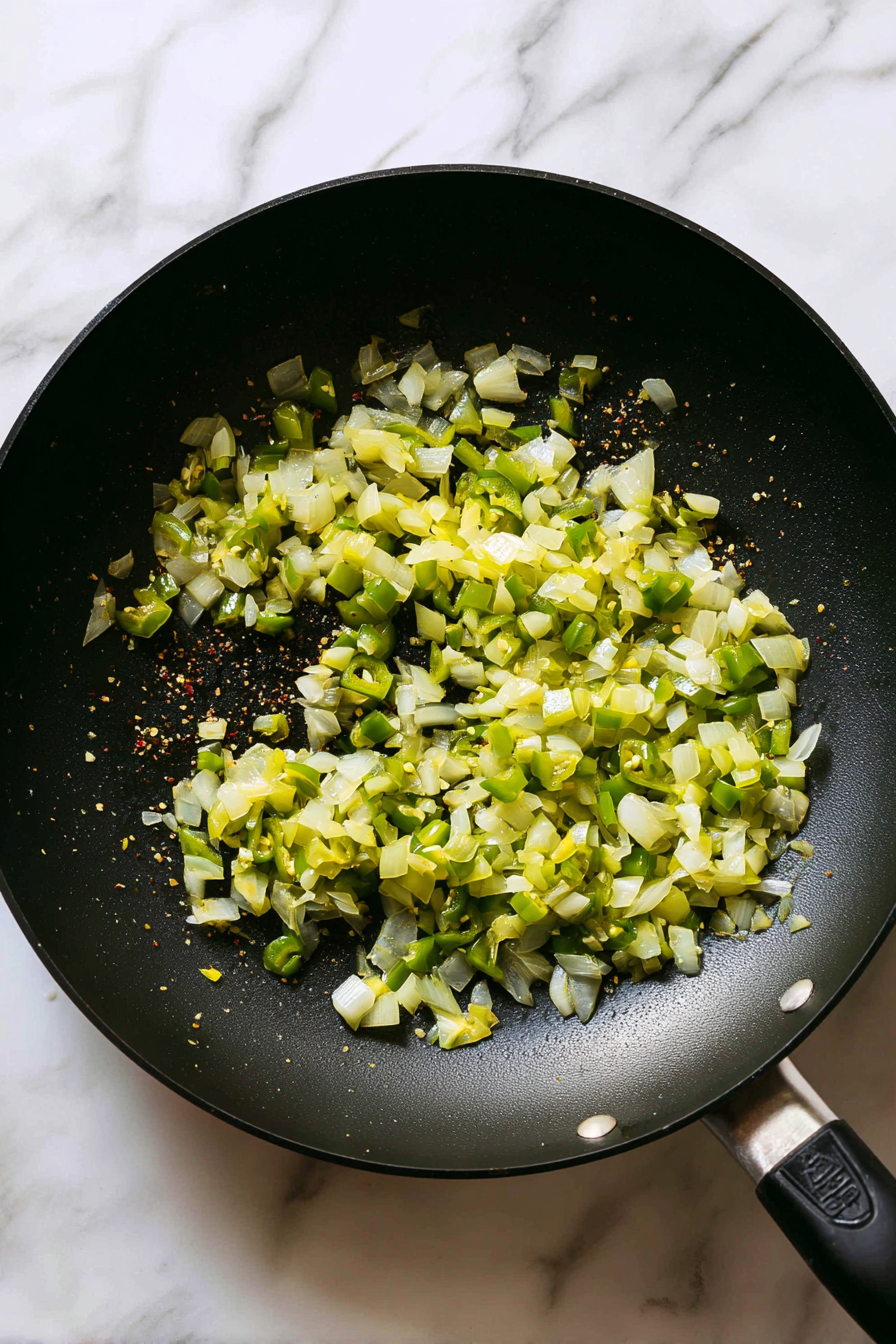 Toss in diced onions, green chilies, and sauté until onions turn soft.