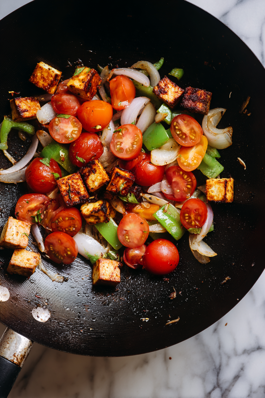 In another pan, stir-fry paneer cubes, onion, capsicum, and tomato in a bit of oil with garam masala.